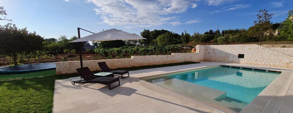 une piscine avec deux chaises et un parasol dans l'établissement Trulli Martina, à Martina Franca