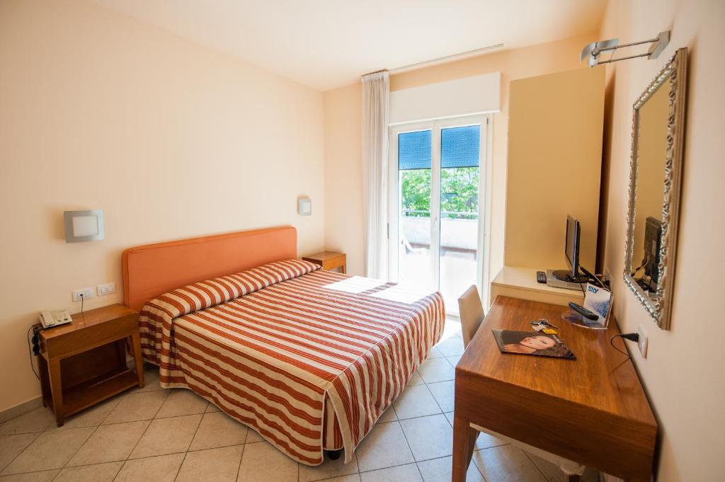 une chambre avec un lit, un bureau et une télévision dans l'établissement Alba Hotel, à Marina di Ravenna