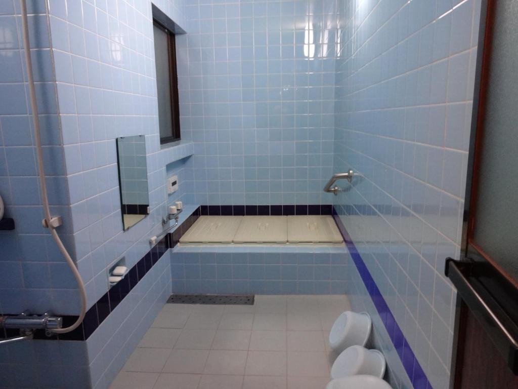 - une salle de bains carrelée de bleu pourvue d'une baignoire et d'une fenêtre dans l'établissement Ryokan Uemura, à Kyoto