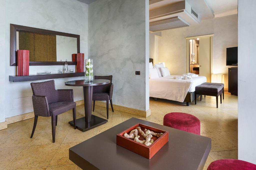 une chambre d'hôtel avec un lit, une table et des chaises dans l'établissement Romano Palace Luxury Hotel, à Catane
