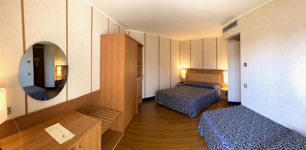 une petite chambre avec deux lits et un miroir dans l'établissement Nicotel Barletta, à Barletta