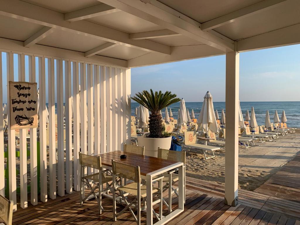une terrasse en bois avec une table et des chaises sur la plage dans l'établissement Villaggio Benvivere, à Senigallia