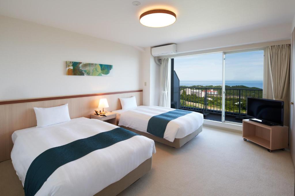 une chambre d'hôtel avec deux lits et une fenêtre dans l'établissement Hotel Village Izukogen, à Itō
