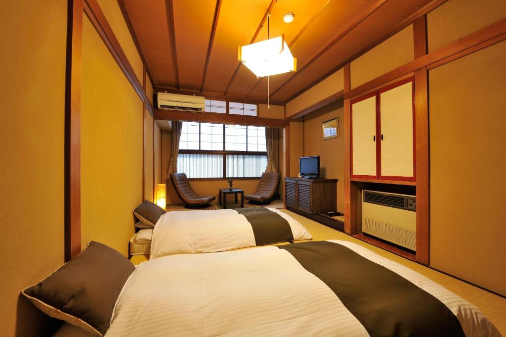 une chambre d'hôtel avec deux lits et une télévision dans l'établissement Hida Takayama Hodakaso Yamano Iori, à Takayama