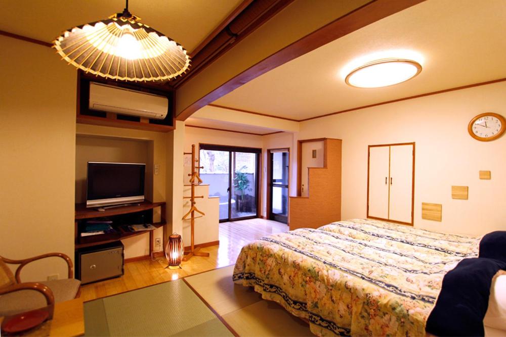 - une chambre avec un grand lit et une télévision dans l'établissement Masutomi Ryokan, à Hakone