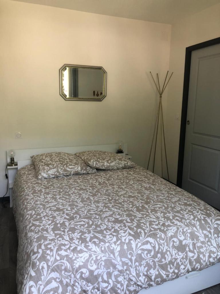 une chambre avec un lit et un miroir au mur dans l'établissement Appartement refait à neuf 40m2, Cauterets Centre, à Cauterets