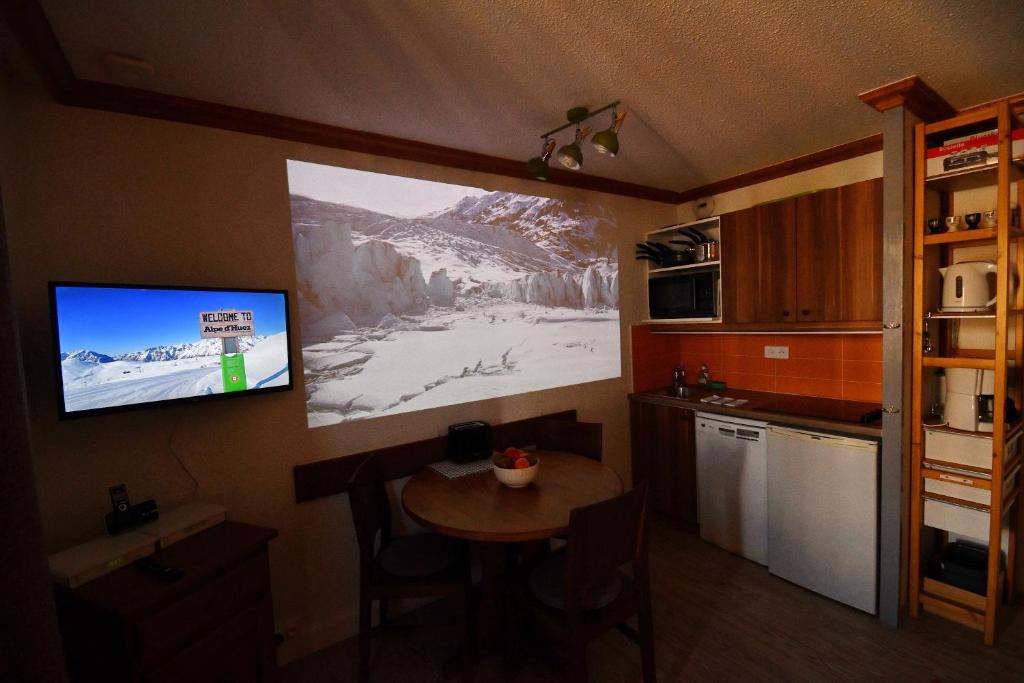 Il comprend une cuisine avec une petite table et une télévision murale. dans l'établissement Superb view+Swim Pool+Smart TV+Netflix+Projector, à Huez 23 autres photos
