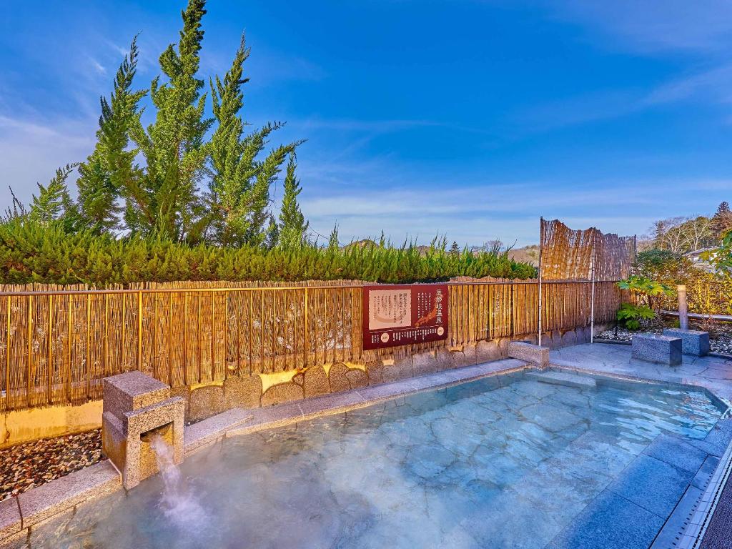 - une piscine dans un jardin avec une clôture en bois dans l'établissement Ooedo Onsen Monogatari Enakyo, à Ena
