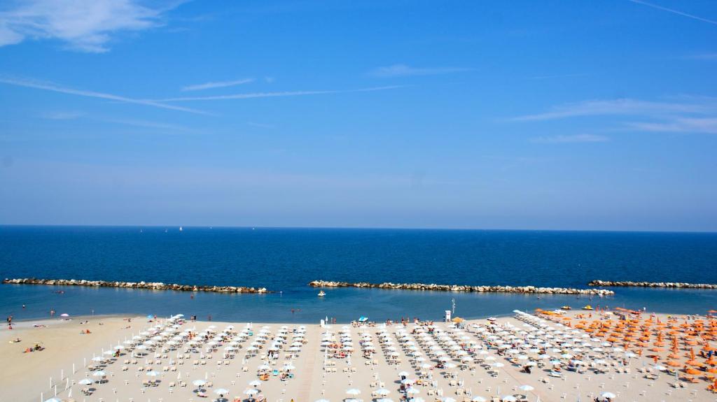 une plage avec beaucoup de parasols et de personnes dans l'établissement Hotel Palazzo Caveja, à Rimini