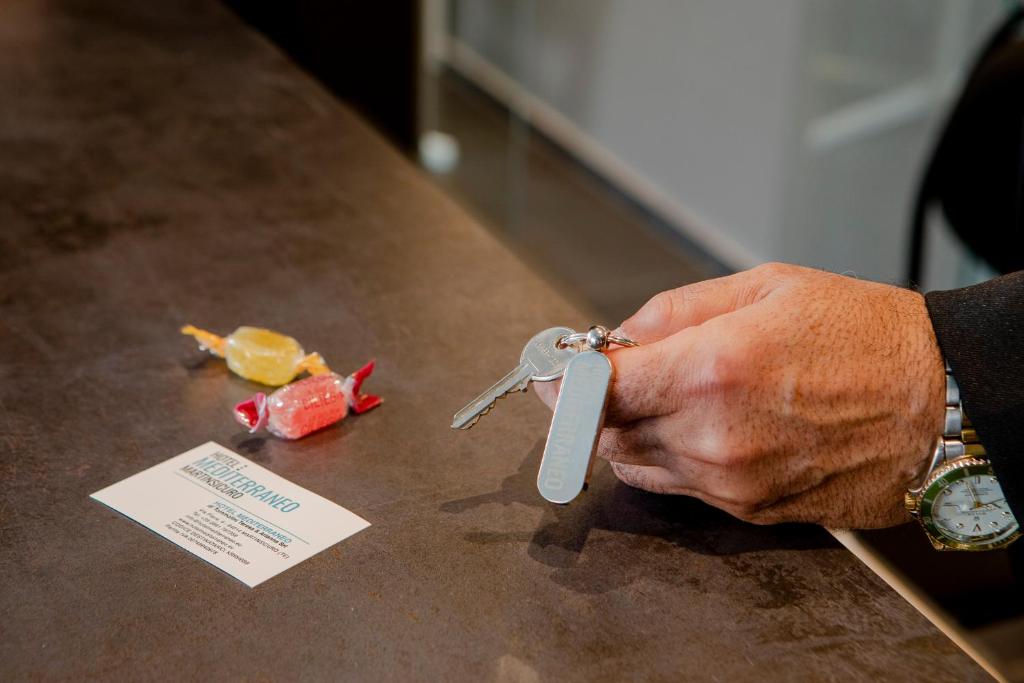 une personne tenant une paire de ciseaux sur une table dans l'établissement Hotel Mediterraneo, à Martinsicuro