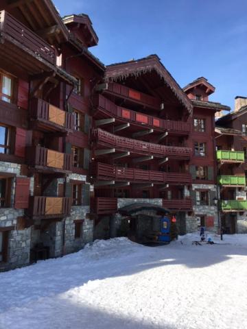 un grand bâtiment avec de la neige devant lui dans l'établissement Superbe appart Arc 1950 4/6pers dans résidence hôtelière 5* - Skis aux pieds, à Arc 1950