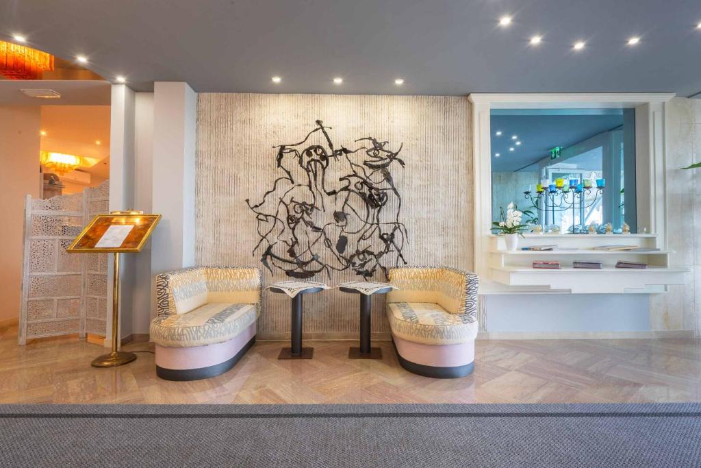 une chambre avec deux chaises et un mur orné d'une peinture dans l'établissement Hotel Doriana, à Caorle