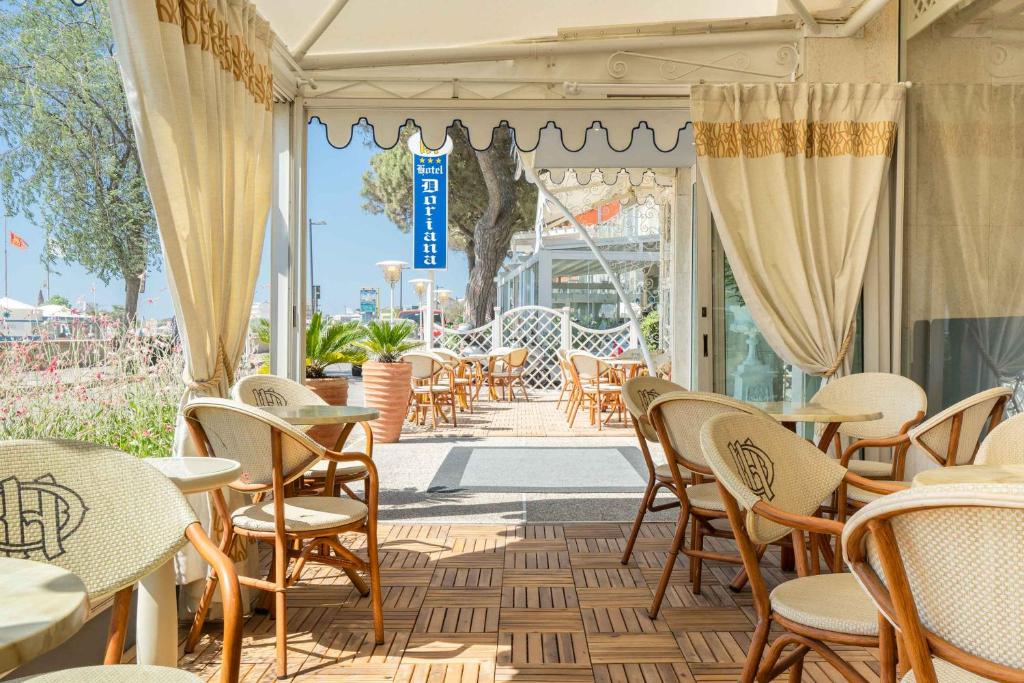 une terrasse avec tables et chaises dans un restaurant dans l'établissement Hotel Doriana, à Caorle