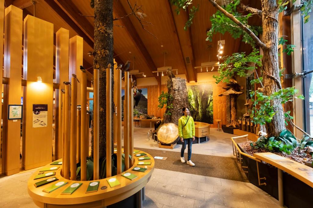 Un homme est debout dans un bâtiment avec des arbres dans l'établissement Kyukamura Shikotsuko, à Chitose
