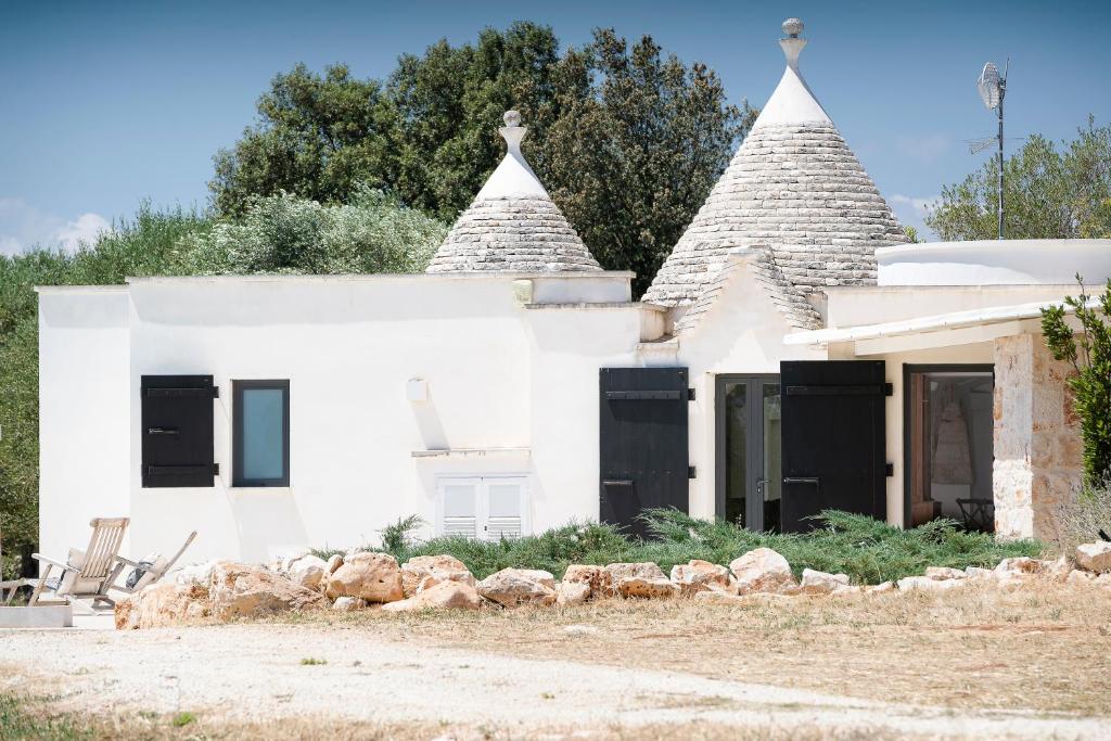 une maison blanche avec volets noirs dans l'établissement trullo and lamia cinera, à Cisternino