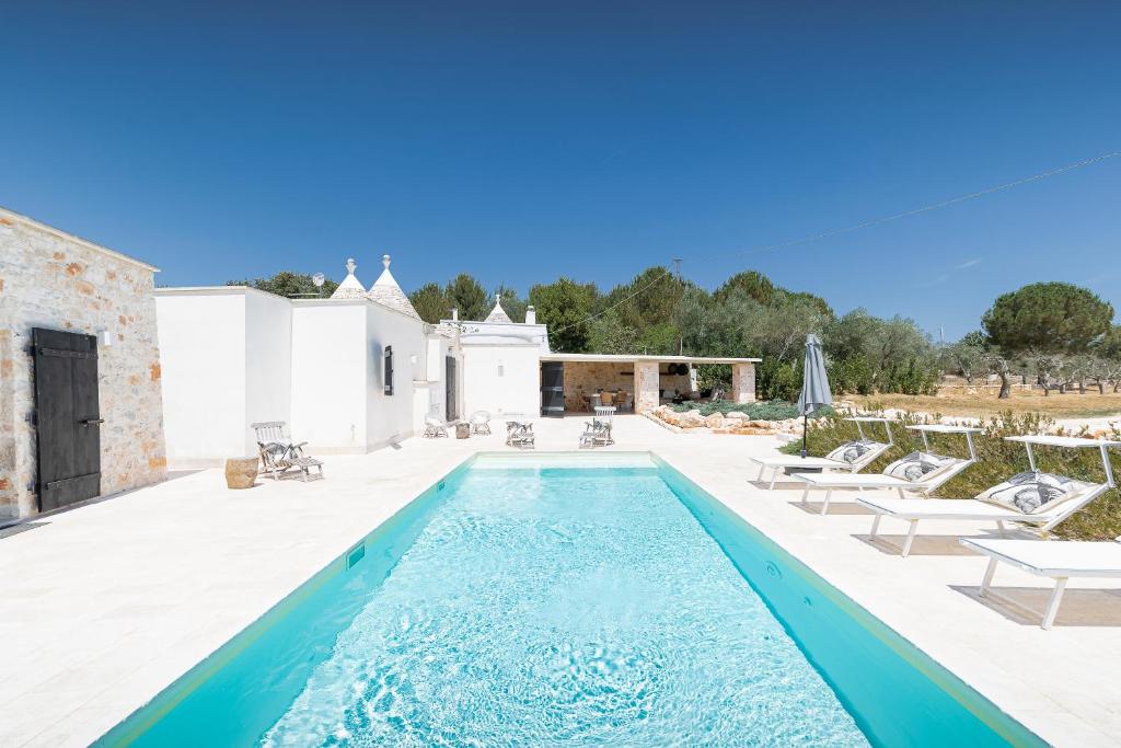 - une piscine avec des chaises longues sur la terrasse dans l'établissement trullo and lamia cinera, à Cisternino