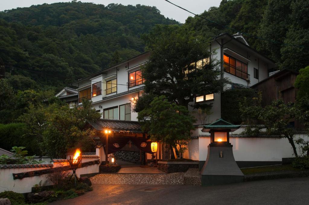 une grande maison avec des lumières devant elle dans l'établissement Beppu Showaen, à Beppu