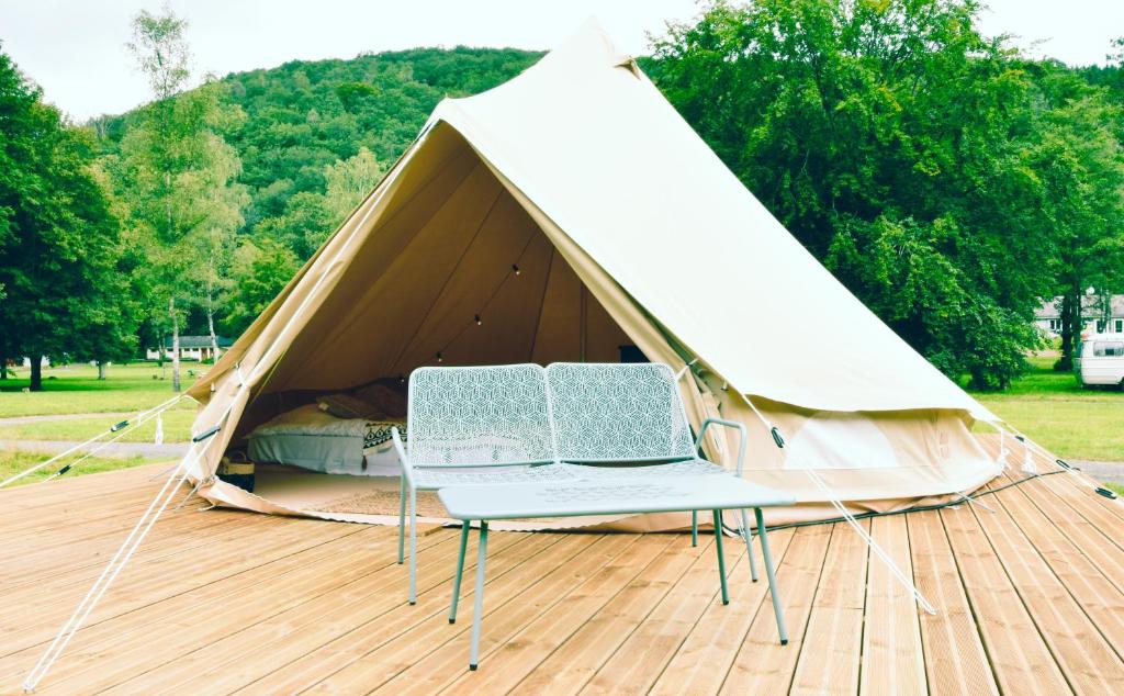 une tente avec 2 chaises sur une terrasse en bois dans l'établissement Les Insolites du Domaine d'Haulmé, à Haulmé 36 autres photos