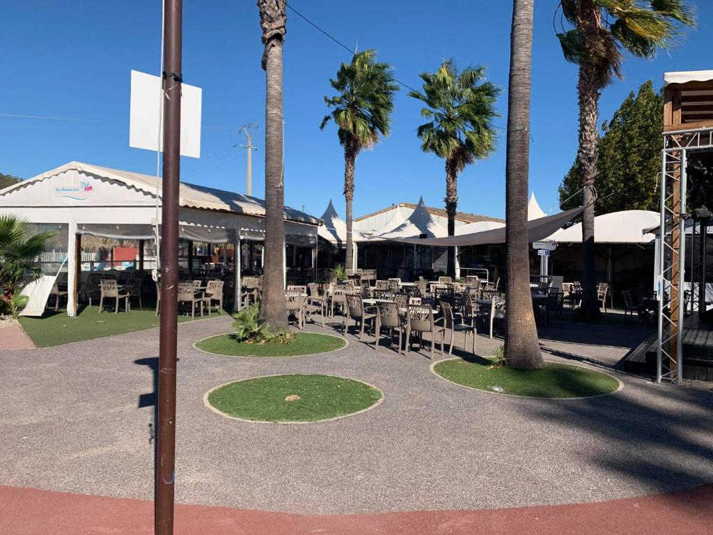 un patio avec tables, chaises et palmiers dans l'établissement Camping Le Montourey, à Fréjus