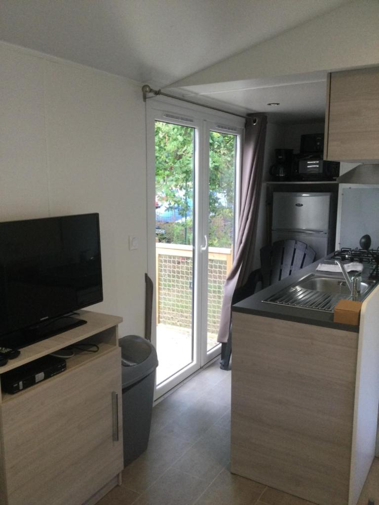 une cuisine avec une télévision et une cuisine avec une porte coulissante en verre dans l'établissement camping marvilla parks 4 etoiles, à Aureilhan