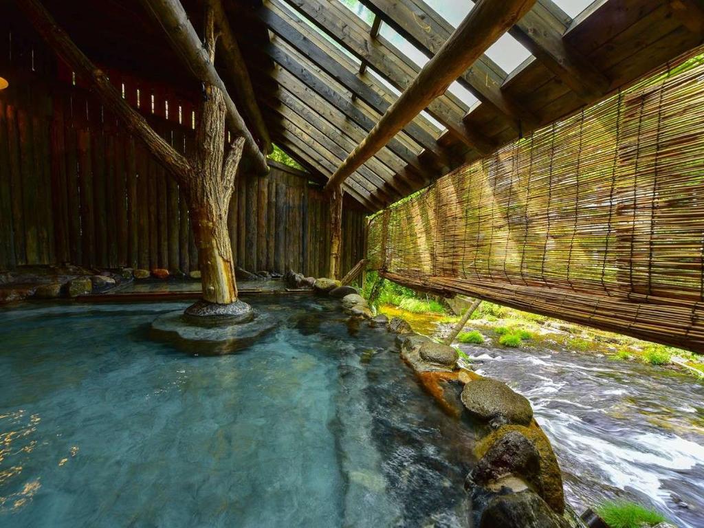 une petite piscine d'eau avec un arbre. dans l'établissement Kutsurogijyuku Shintaki, à Aizuwakamatsu