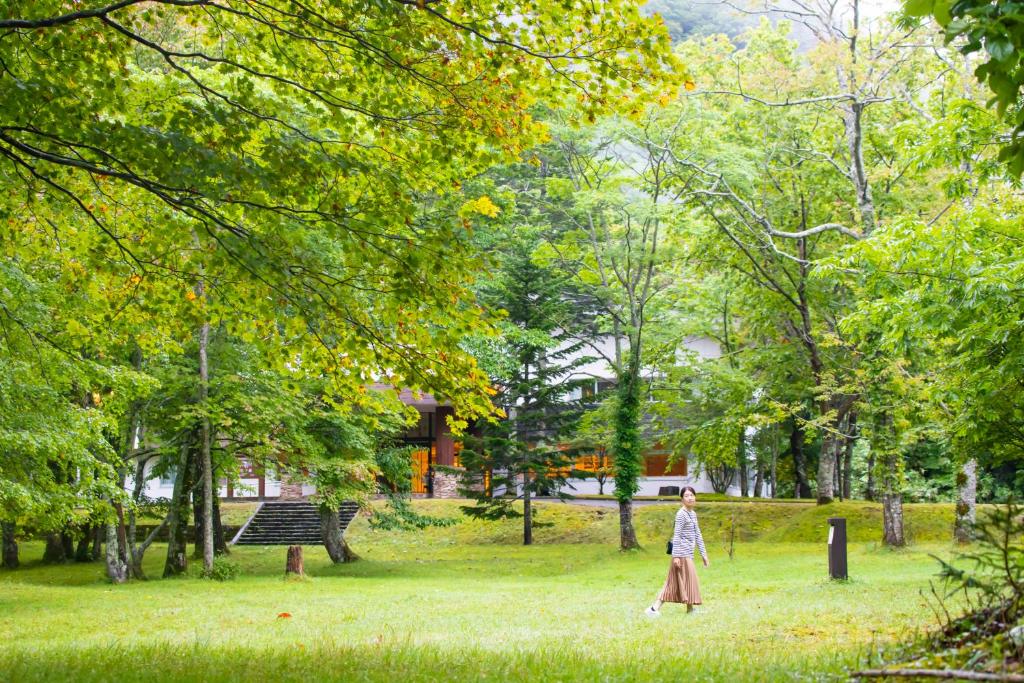 Une femme qui marche dans un parc dans l'herbe dans l'établissement Kyukamura Shikotsuko, à Chitose