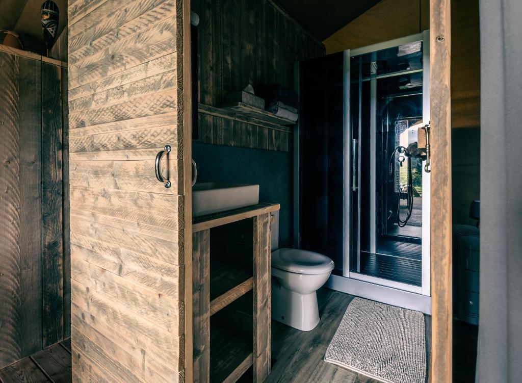 une salle de bain avec toilettes et porte en bois dans l'établissement Lodges des Grands Chênes, à Andelarrot