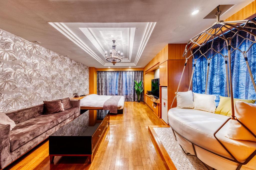 un salon avec un canapé et un lit dans l'établissement HOTEL ARTIA DINOSAUR GIFU -Adult Only, à Rokujō
