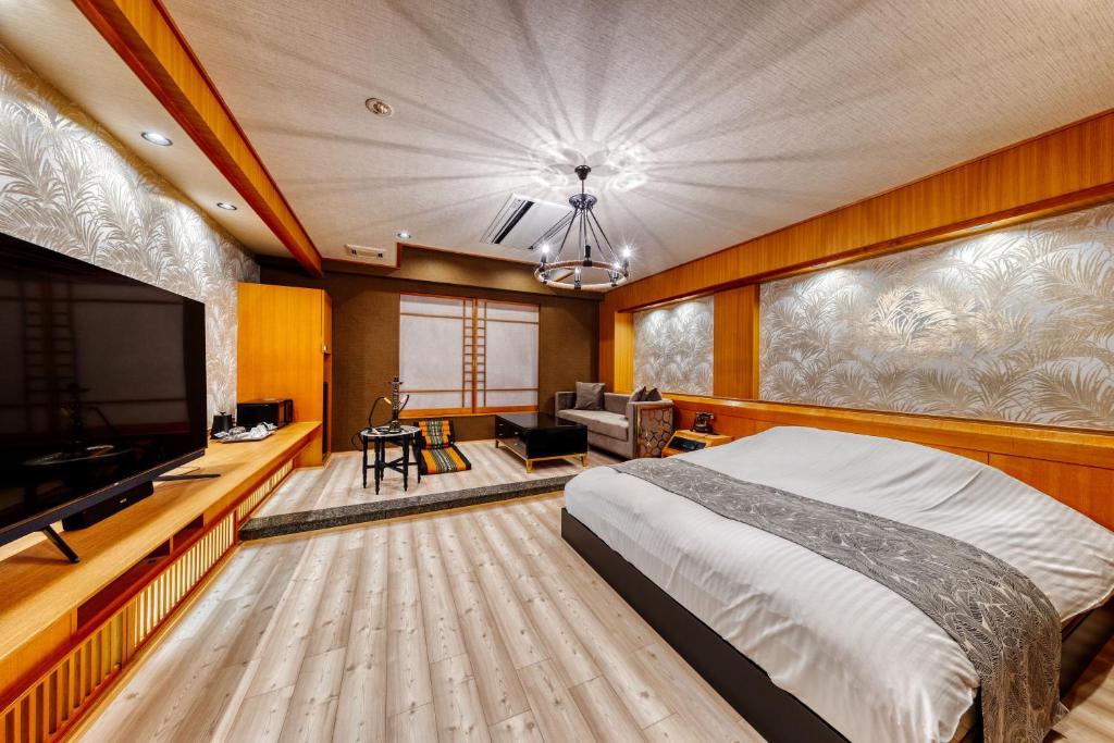 une chambre avec un grand lit et une télévision à écran plat dans l'établissement HOTEL ARTIA DINOSAUR GIFU -Adult Only, à Rokujō