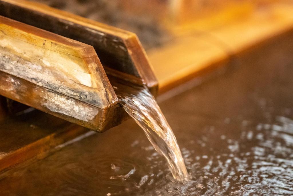 un flux d’eau provenant d’un conteneur en bois dans l'établissement Shibu Onsen KADOYA, à Yamanouchi
