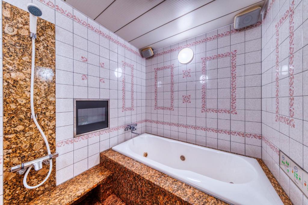 une salle de bain avec une baignoire et une télévision au mur dans l'établissement HOTEL sala del rey namba -Adult Only, à Osaka 6 autres photos
