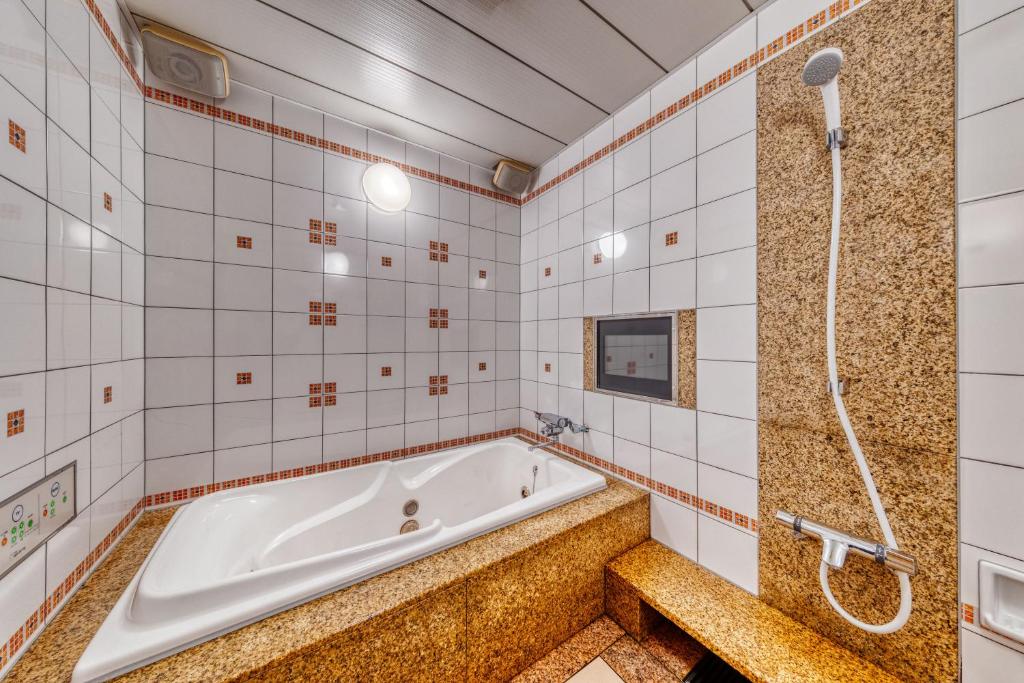La salle de bains est pourvue d'une baignoire et de carrelage blanc. dans l'établissement HOTEL sala del rey namba -Adult Only, à Osaka