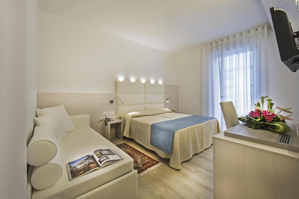 une chambre d'hôtel avec un lit et un canapé dans l'établissement Hotel Hollywood***S, à Lido di Jesolo