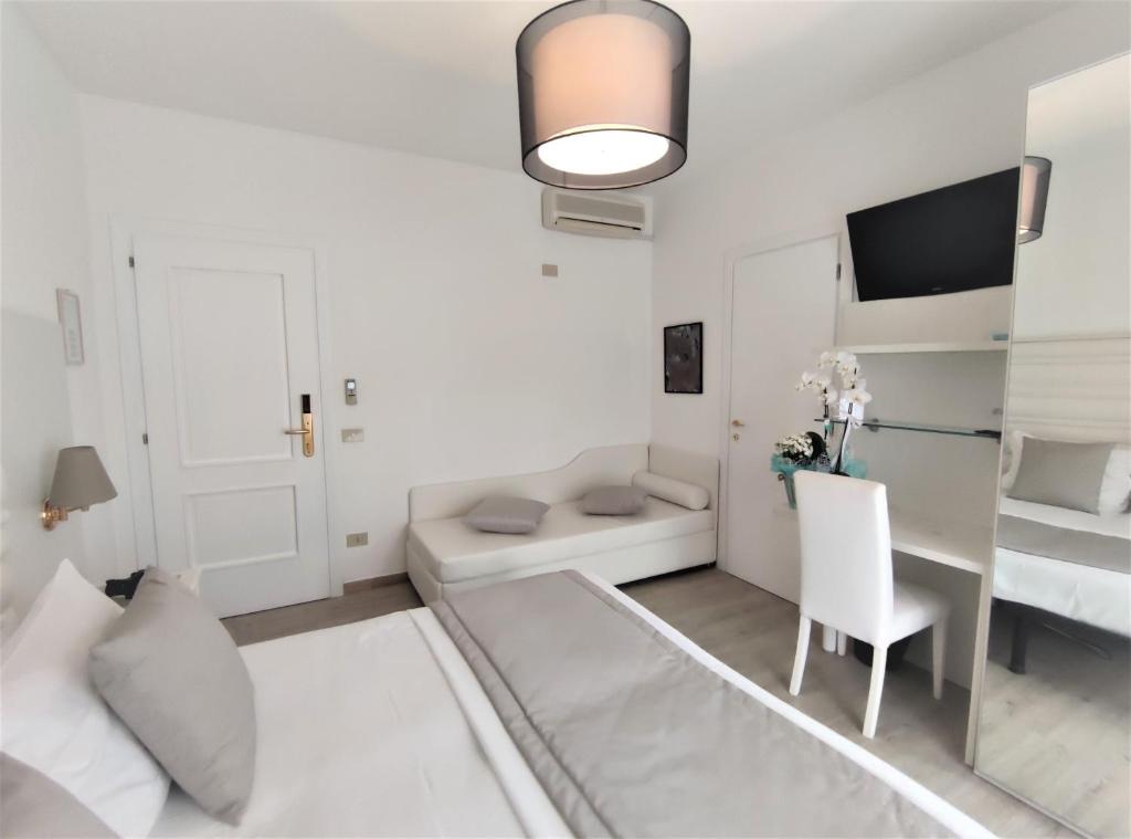 un salon blanc avec un bureau et une chaise dans l'établissement Hotel Rossini 4S, à Lignano Sabbiadoro