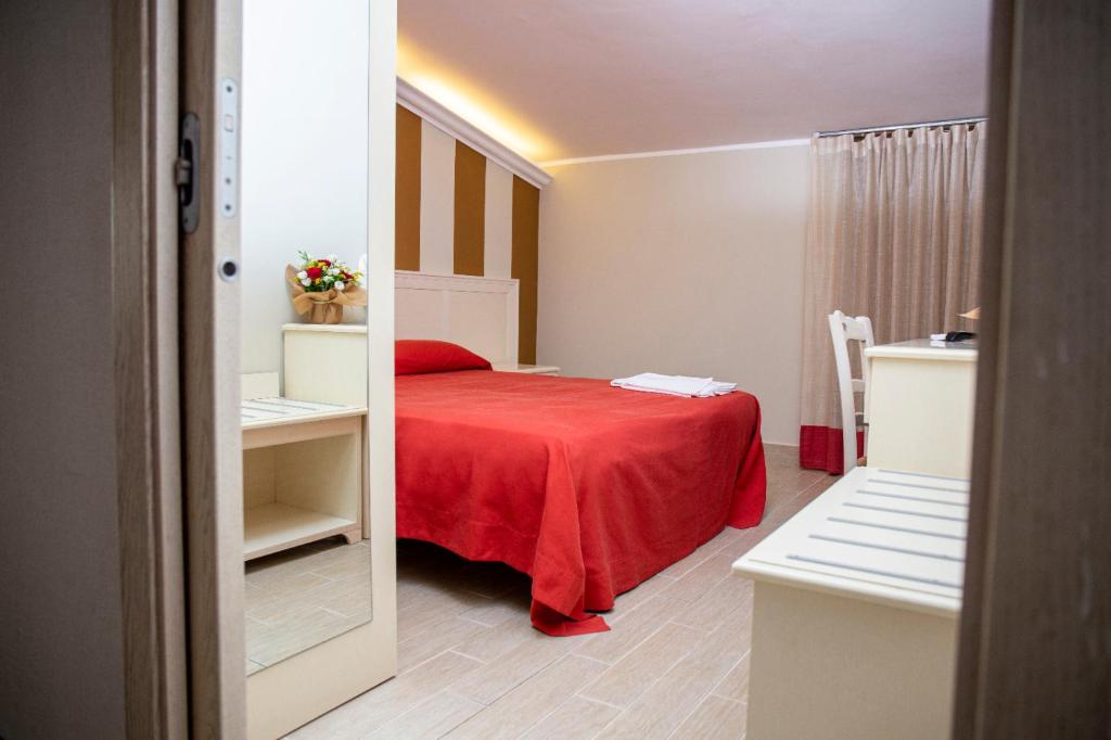 une chambre avec un lit avec une couverture rouge dans l'établissement Hotel Al Rustico, à Crosia