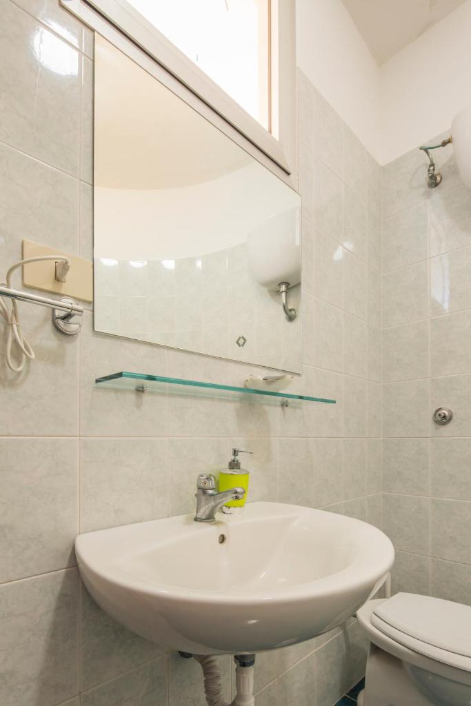 une salle de bain avec un lavabo et un miroir et des toilettes dans l'établissement Hotel Rosy, à Battipaglia