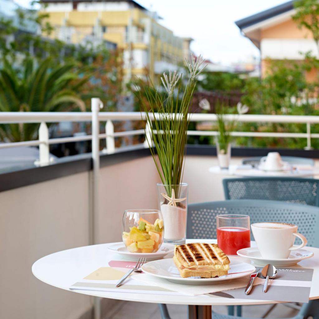 une table avec deux assiettes de nourriture et de boissons sur un balcon dans l'établissement Art Hotel Principe, à Lignano Sabbiadoro