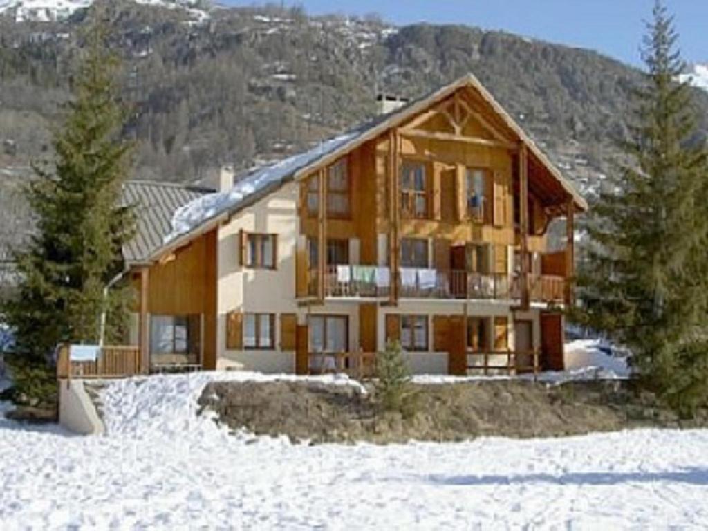 une grande maison en bois avec de la neige au sol dans l'établissement Marmotte Le Monêtier Apartment, au Monêtier-les-Bains