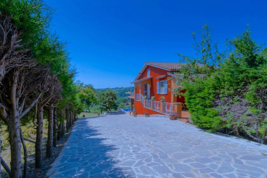 une route pavée menant à une maison rouge dans l'établissement luxury villa Arianna, à Tarano