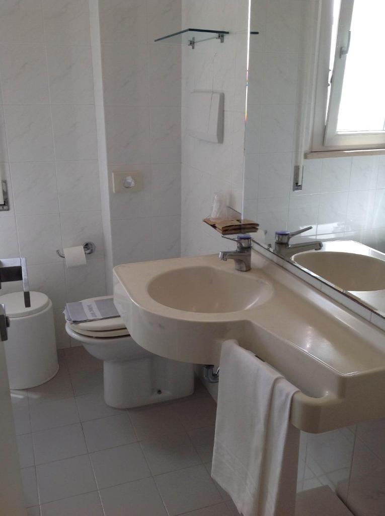 une salle de bain blanche avec un lavabo et des toilettes dans l'établissement GFH - Hotel Ruhig, à Marotta