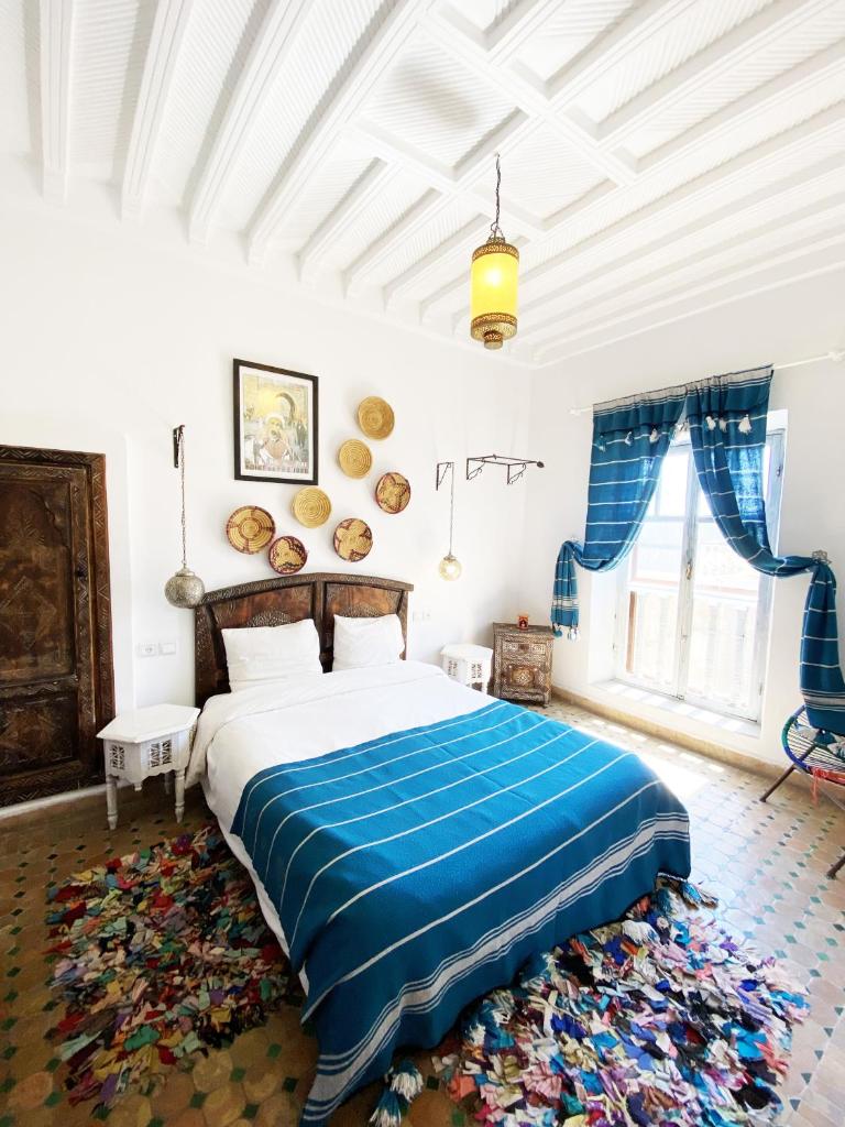 une chambre avec un grand lit avec une couverture bleue dans l'établissement Riad Inna & Watersports Center, à Essaouira