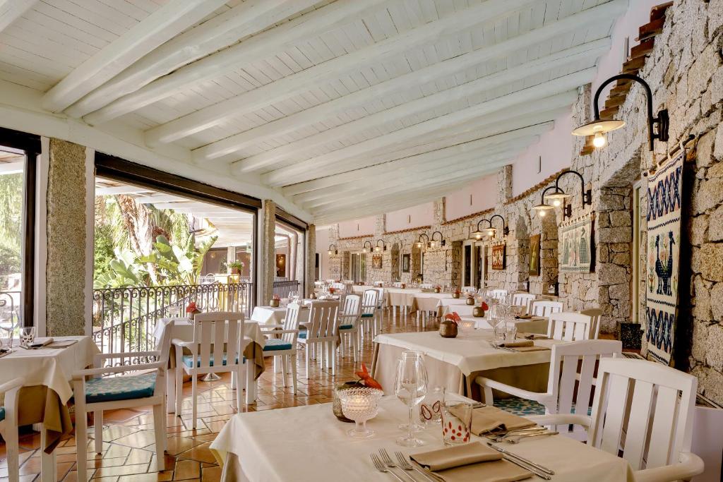 un restaurant avec des tables blanches et des chaises blanches dans l'établissement Cruccùris Resort - Adults Only, à Villasimius