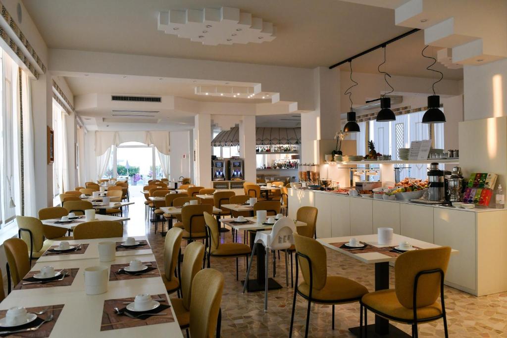 un restaurant avec des tables et des chaises et un bar dans l'établissement Hotel Delle Mimose, à Lido di Jesolo