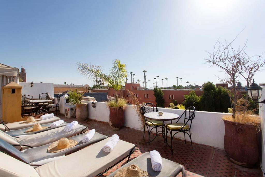 - une rangée de chaises longues et une table sur le toit dans l'établissement Riad Lakhdar, à Marrakech