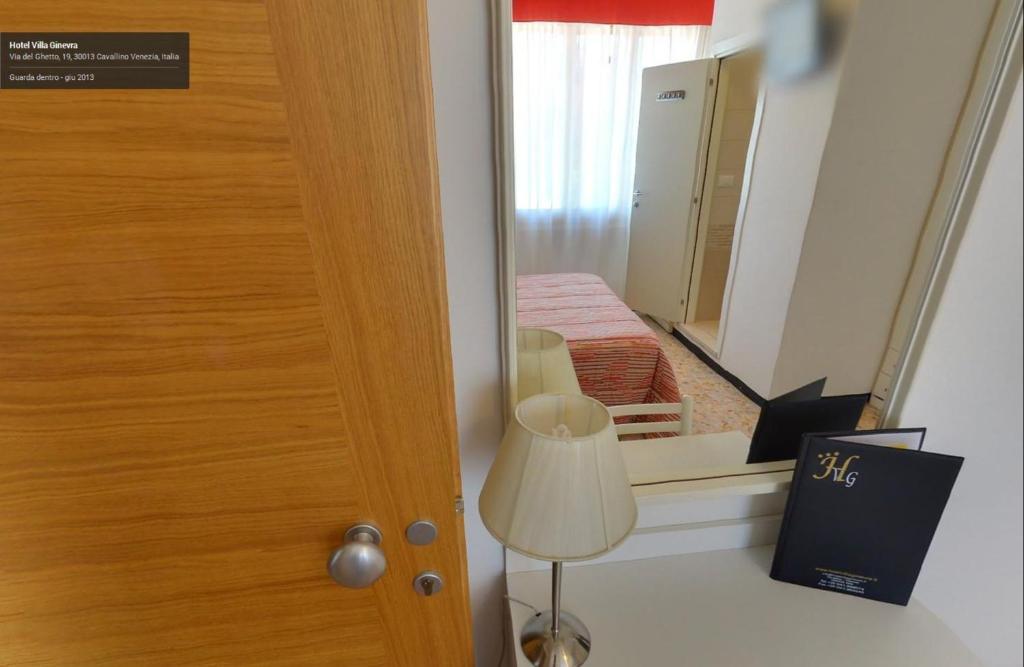 Cette chambre comprend une porte, un miroir et une lampe. dans l'établissement Hotel Villa Ginevra, à Cavallino-Treporti