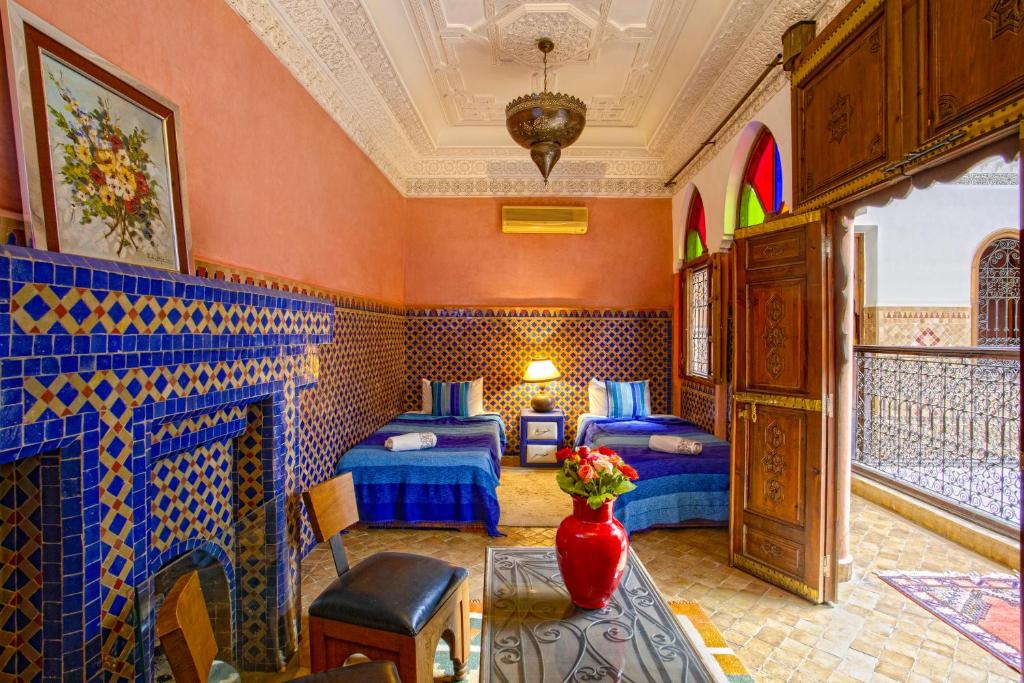 Cette chambre comprend 2 lits et un vase de fleurs sur une table. dans l'établissement Riad Lakhdar, à Marrakech