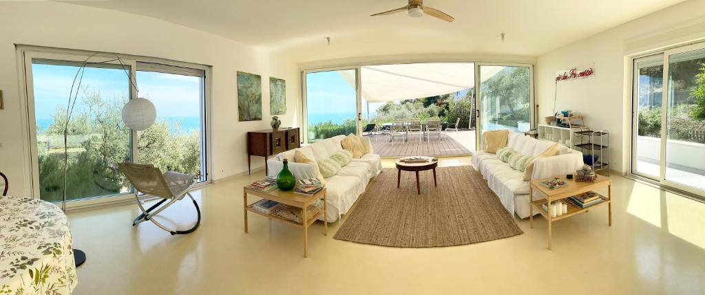 Elle comprend un salon doté d'un mobilier blanc et de grandes fenêtres. dans l'établissement Stunning Design Villa with unique 180º sea views, à Marina di San Vito