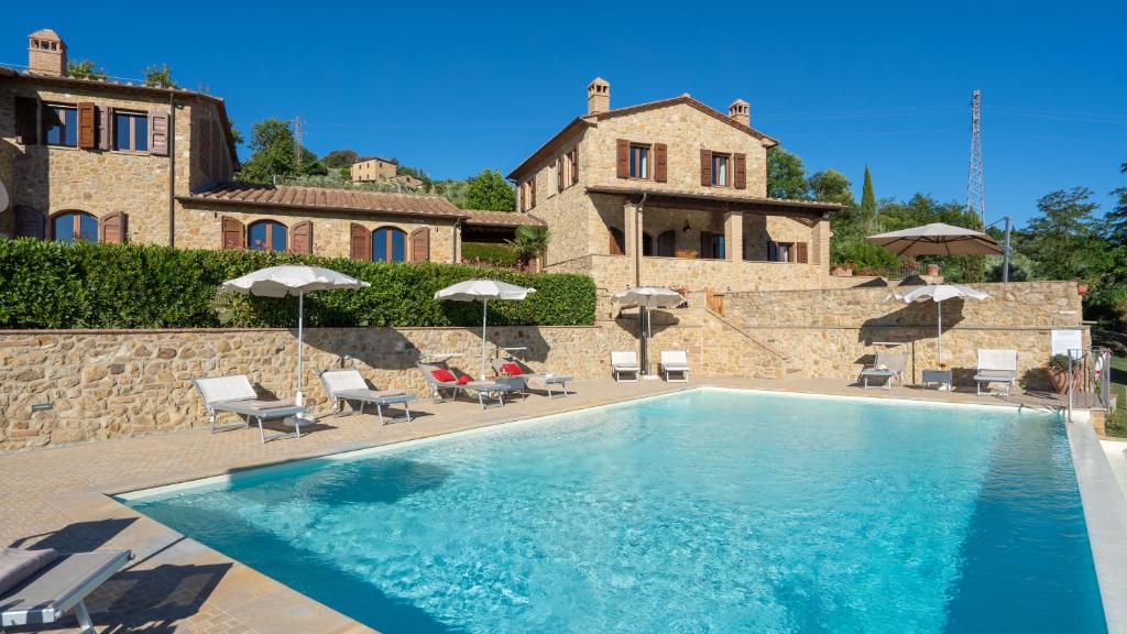 une piscine avec chaises et parasols devant un immeuble dans l'établissement La Vecchia Fonte 15, Emma Villas, à Volterra