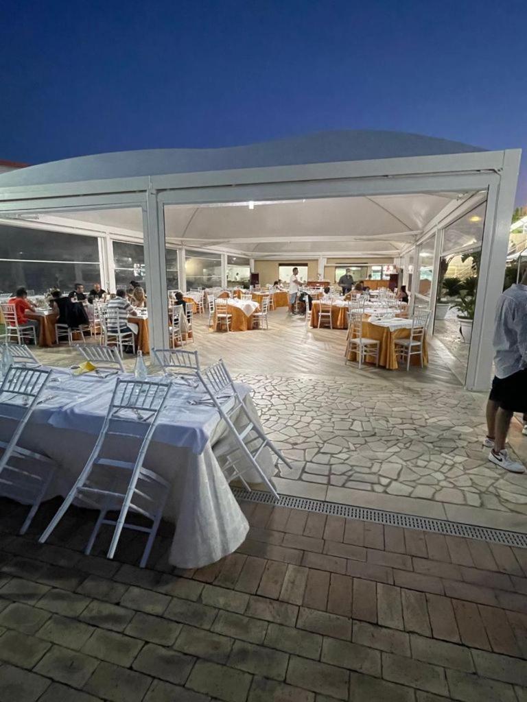 un pavillon avec des tables et des chaises et des gens dans un restaurant dans l'établissement Hotel Il Corsaro, à Le Castella