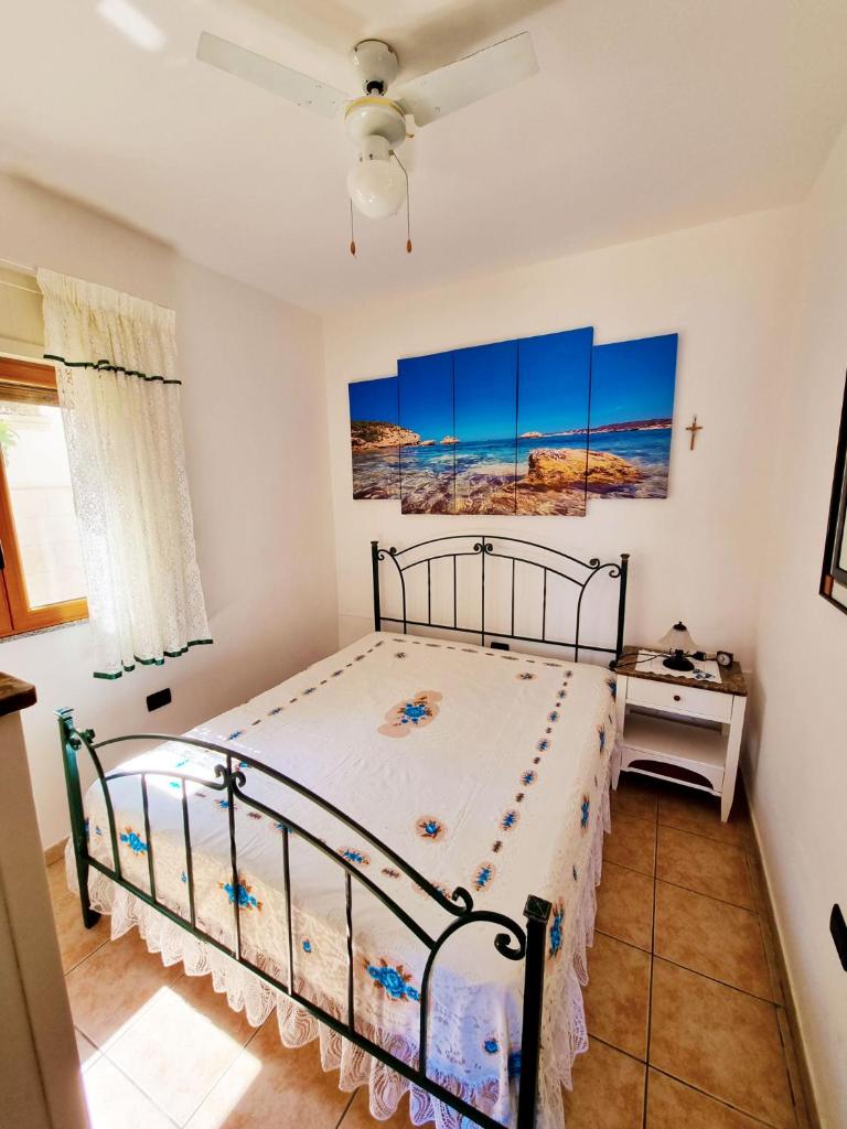 une chambre avec un lit et un ventilateur de plafond dans l'établissement Villetta Azzurra, à Corsano